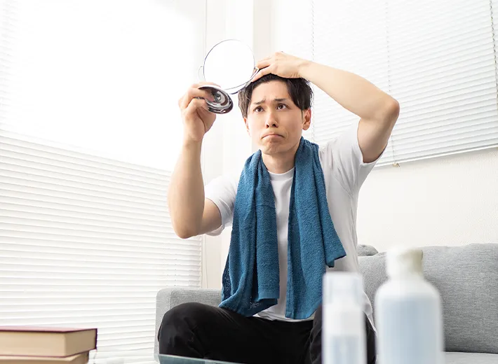 鏡で生え際を見る男性